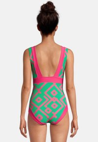 Maillot de bain une pièce vert avec des motifs géométriques roses, dotée de larges bretelles et d'un design à dos bas. Texture de tissu lisse, couleurs vives.