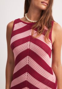 Kootud kleit, millel on sobiv disain, maroonide ja helesiniste vöötide ning avatud kudumise struktuur, ümar kaelus.