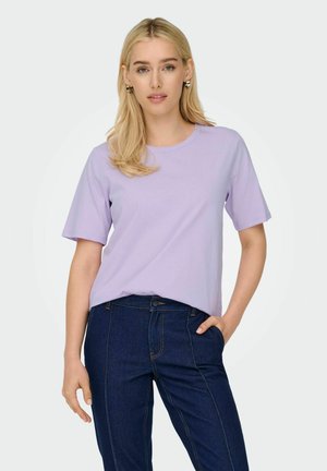 Helles lila T-Shirt mit kurzen Ärmeln und rundem Halsausschnitt, kombiniert mit dunkelblauen Denim-Jeans, die kontrastierende Nähte aufweisen.