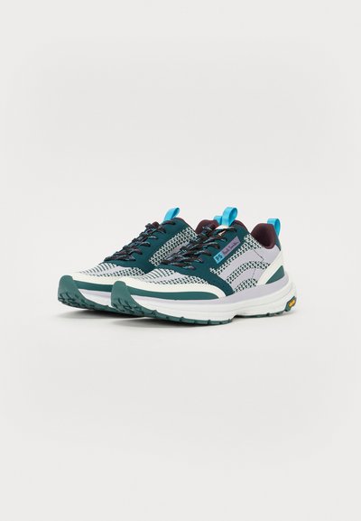 Sport sneakers med et mesh-overdel i mørk teal og hvit, teksturerte detaljer, og en tykk hvit såle. Har teal snøringer og løftekroker.