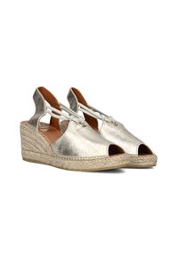 Metallic silver espadrille wedges with open toes, stitched jute detailing, and tie accents at the heel. Soft inner lining.