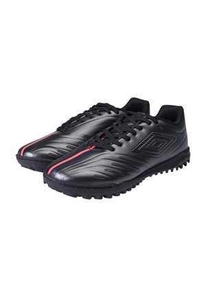 Paire de chaussures de sport noires avec semelles texturées, lacets noirs et détail d'une bande rouge au centre devant sur fond blanc.