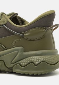 Zelená sportovní bota s texturovanou gumovou podrážkou, svrškem z textilu a kůže, zesíleným šitím a polstrovaným límcem pro pohodlí.