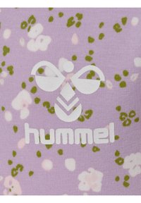 Lila tyg med ett blommönster i grönt och rosa. Framträdande vitt logo med stiliserad design och "hummel" text längst ner.