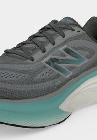 Γκρι και τιρκουάζ αθλητικό παπούτσι New Balance με αναπνεύσιμο πάνω μέρος από δίχτυ, μπροστινή δέση με κορδόνια και μαλακή τιρκουάζ μεσαία σόλα.