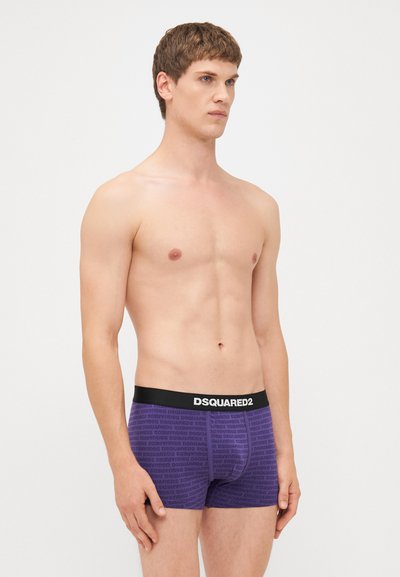 Fioletowe bokserki z czarnym pasem, na którym widnieje logo "DSQUARED2"; wykonane z elastycznego materiału z powtarzającym się wzorem tekstowym.