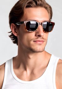 Occhiali da sole con montatura tartarugata, dettagli verdi e lenti scure. Il design presenta una forma quadrata moderna con una finitura lucida.