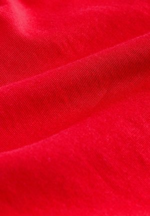 Tessuto di cotone rosso con una texture liscia, caratterizzato da delicati motivi a coste. La superficie appare uniforme, con una saturazione dei colori vivace.