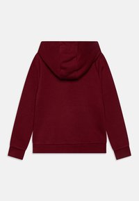 Sudadera burdeos con una textura suave, que presenta capucha con cordón, mangas largas y un corte relajado. Sin logotipos ni patrones visibles.