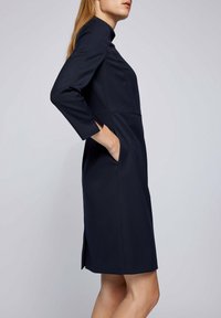 Námořnické šaty s vysokým výstřihem, tříčtvrtečními rukávy a postranními kapsami. Vyrobeno z texturované látky s přizpůsobenou siluetou a rozparky na lemu.