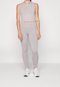 Ljust grå träningstopp med rund hals och matchande högmidjade leggings, båda med subtil märkning och texturerade detaljer.