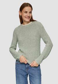 Hellgrüner Strickpullover mit langen Ärmeln, gerippten Bündchen und rundem Halsausschnitt, kombiniert mit blauer Jeans. Strukturmuster überall.