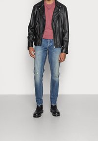 Chaqueta de motorista de cuero negro, camiseta burdeos, jeans claros desgastados y botas de tobillo negras. Ajuste slim, diseño clásico, textura suave.