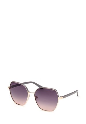 Gafas de sol hexagonales con lentes en degradado púrpura oscuro, acentos metálicos dorados y brazos de plástico gris con marca en un lado.