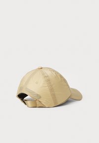 Cappellino da baseball beige realizzato in tessuto leggero e lucido. Presenta una visiera curva, una fascetta regolabile sul retro e fori di ventilazione sui lati.