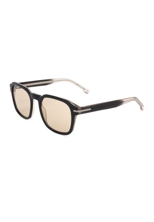 Occhiali da sole con montatura quadrata nera, lenti marrone chiaro e aste nere e beige leggermente traslucide.