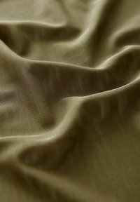 Olivgrüner Stoff mit einer strukturierten, leicht zerknitterten Oberfläche. Das Material wirkt leicht und atmungsaktiv und weist ein subtil strukturiertes Netzmuster auf.