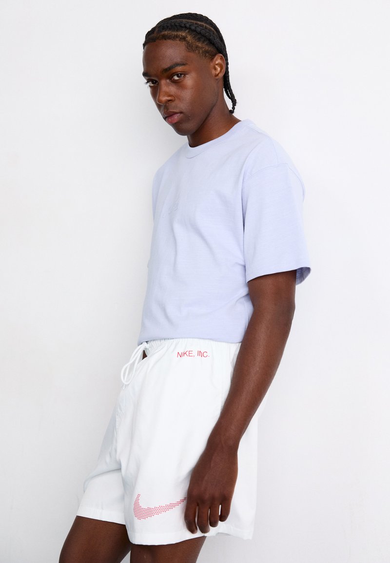 Helles lila Baumwoll-T-Shirt und weiße Shorts mit rotem "Nike, Inc." Logo und Punktdesign an der Seite, mit elastischem Bund.