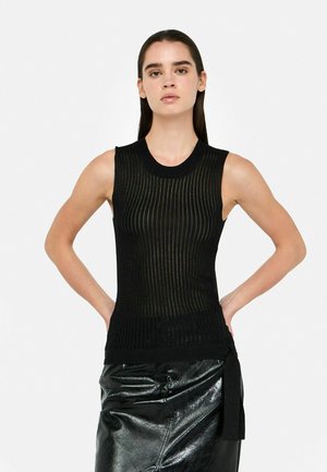 Top nero senza maniche con texture rigata orizzontale, scollo rotondo, design aderente e fascia in vita. Abbinato a una gonna avvolgente nera lucida.