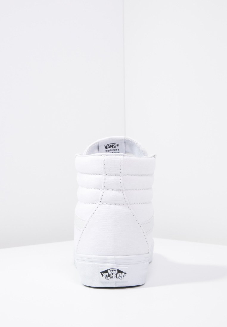 Zapatillas altas blancas de lona con cuello acolchado, que presentan una etiqueta de logo negra en el talón y sutiles detalles de costura.