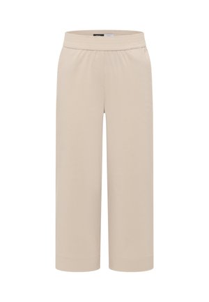 Beżowe spodnie o szerokich nogawkach z elastycznym pasem i mankietami u dołu, prezentowane na jednolitym białym tle.