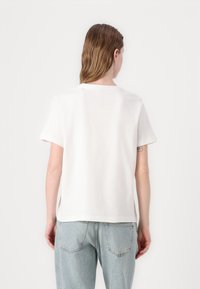 Hvid bomulds t-shirt med korte ærmer, rund halsudskæring og en afslappet pasform. Stoffet ser blødt og let tekstureret ud.