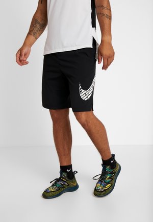 Czarne szorty z białym logo Nike w wzór cegły, zestawione z kolorowymi sneakersami o teksturowanym wzorze i matowymi czarnymi akcentami.