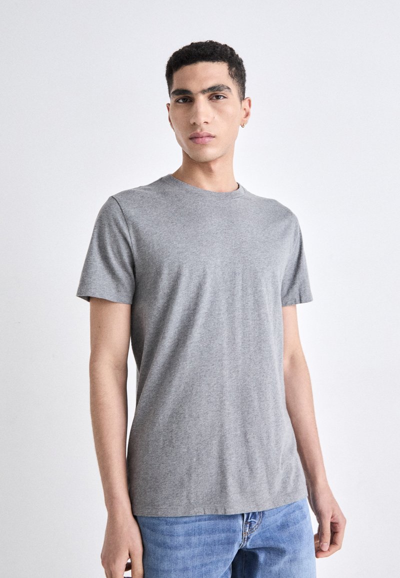 Camiseta de algodón gris con un cuello redondo clásico y mangas cortas, que presenta una forma ajustada y una textura suave.