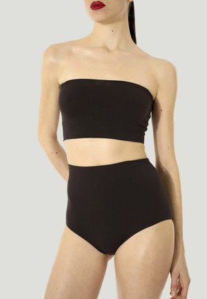 Donna che indossa un top bandeau nero senza spalline e mutandine nere a vita alta su uno sfondo chiaro uniforme.