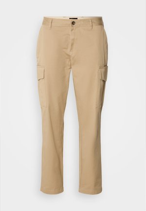 Pantalons cargo beiges en coton. Ils possèdent deux poches latérales, une fermeture à bouton et un design à jambes droites. Texture lisse, style décontracté.