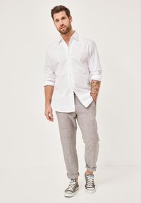 White button-up shirt, light gray patterned pants, cuffed at the ankles, paired with gray sneakers featuring white soles and laces.