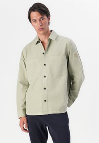 Lichte groene button-up overhemd van katoen, met twee voorzakken, zwarte knopen en een klein stoffen label op de linkermouw.
