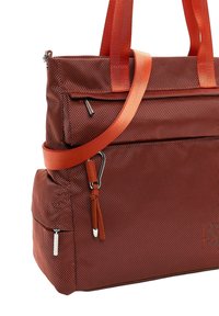 Red textured fabric tote bag with multiple zippered pockets, orange handles, and an adjustable shoulder strap with metal hardware.