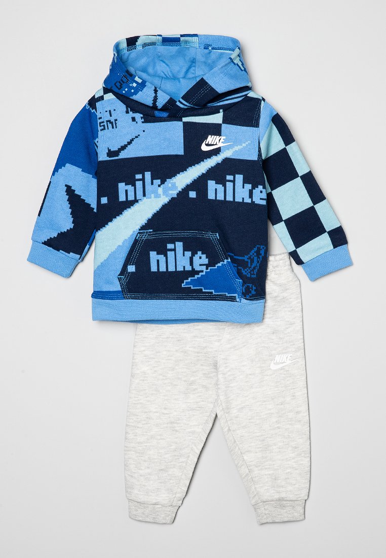 Haut à capuche bleu et marine à motifs avec une poche devant et une capuche, assorti à un pantalon de survêtement gris clair avec un logo Nike.