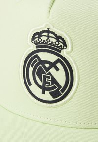 Casquette verte avec un logo Real Madrid brodé en noir, orné d'une couronne, détails élaborés et texture lisse sur un tissu structuré.