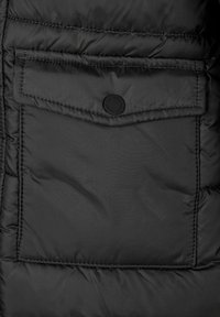 Čierna zateplená bunda s prešívanou textúrou, vreckom s klopou a cvokom a viditeľnými švami.