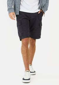 Navy cargo shorts made of lightweight fabric, featuring side pockets and a relaxed fit. Paired with white sneakers with navy accents.