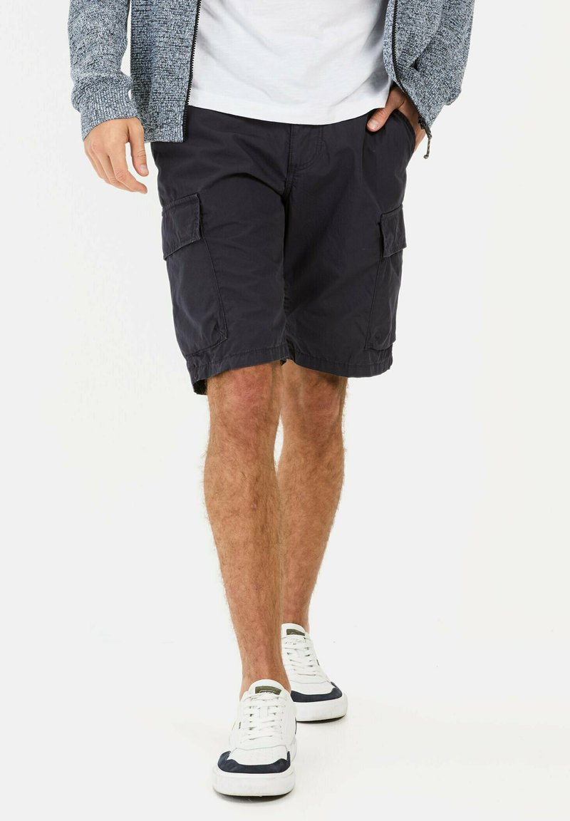 Navy cargo shorts made of lightweight fabric, featuring side pockets and a relaxed fit. Paired with white sneakers with navy accents.