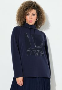 Marinblå långärmad topp med traktörhals, prydd med en strukturerad grafisk design och rhinestones på framsidan. Mjuk ull.