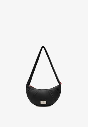 Sac d'épaule noir en forme de croissant avec une texture matelassée, une longue sangle, une fermeture éclair rouge et une étiquette avant portant l'inscription « UNO X VISIONNAIRES ».