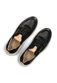Black leather sneakers with textured finish, gold laces, and light-colored soles. Soft inner lining and minimal branding detail.