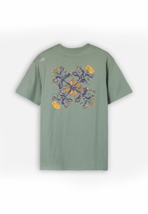 T-shirt en coton vert à manches courtes, avec un motif floral en orange et bleu dans le dos, et un petit logo sur l'épaule.