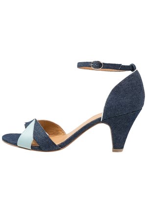 Sandały dżinsowe z jasnoniebieskim akcentem; zamknięta pięta, pasek na kostce z klamrą oraz 6,5-centymetrowym koturnem. Otwarty przód.