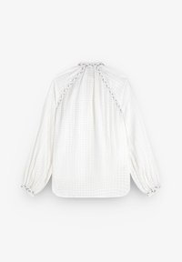 Blusa bianca a maniche lunghe con un motivo a griglia testurizzato, scollatura arricciata e dettagli ai polsini con cuciture in contrasto.
