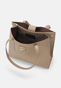 Sac cabas en cuir beige avec fermoir doré, longues anses et poche intérieure zippée affichant le label de la marque Furla.