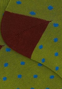 Calzino verde con pois blu e una sezione della punta marrone. Realizzato in tessuto testurizzato con un design a blocchi di colore a contrasto.