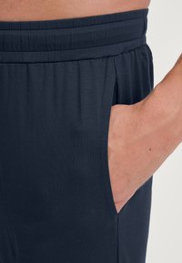 Marineblauwe stoffen stretchbroeken met een elastische tailleband en zijzak, met een gladde textuur en een op maat gemaakte pasvorm.
