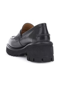 Mocassino in pelle nera con suola robusta e tacco a blocco, cuciture visibili, fodera interna color cuoio, vista angolata dal retro e di lato.