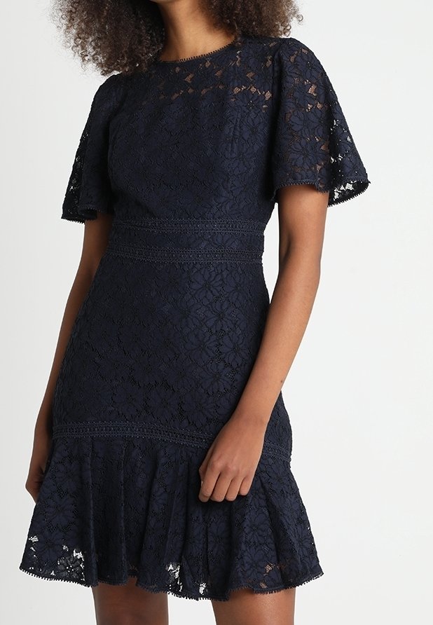 Navy blue lace dress with short flutter sleeves, fitted bodice, and flared hem. Intricate floral pattern and lace trim details.