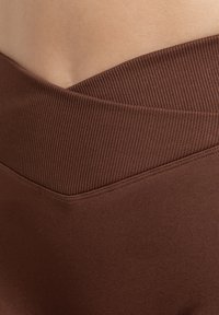 Bruine leggings met een geribde tailleband en een gladde textuur, met een aansluitende pasvorm en een effen kleur zonder patronen.